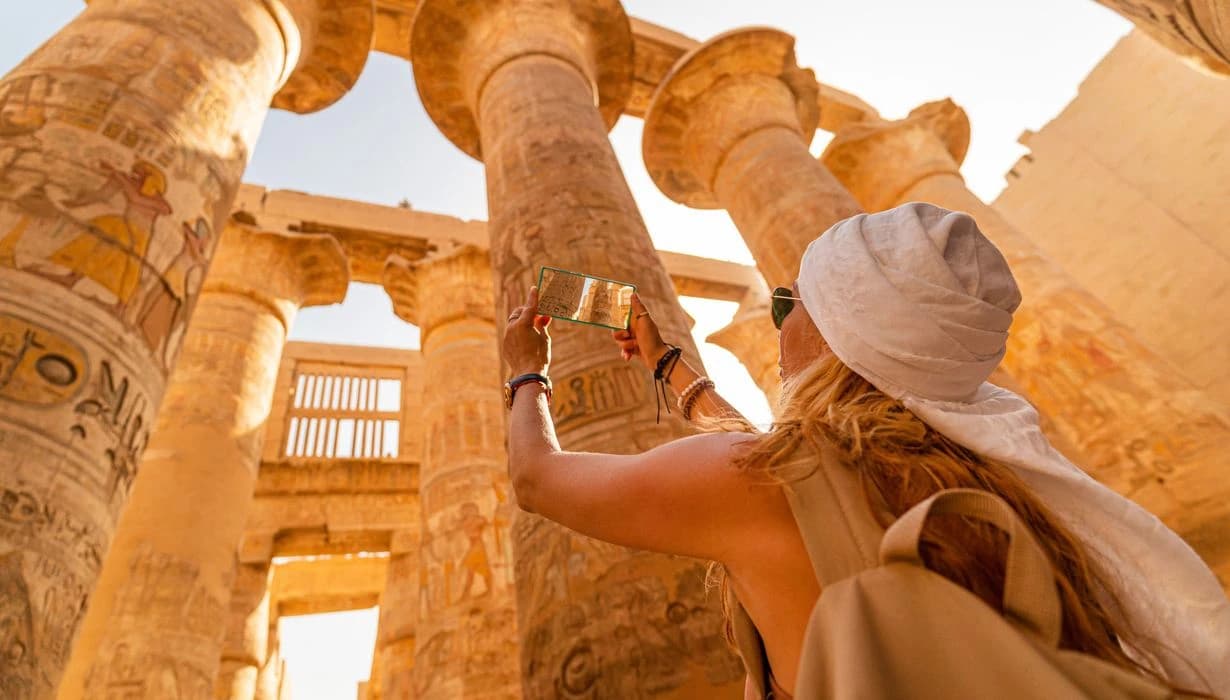 A tourist walks between Pillars of the Great Hypostyle Hall from Karnak Temple, Egypt Tours 